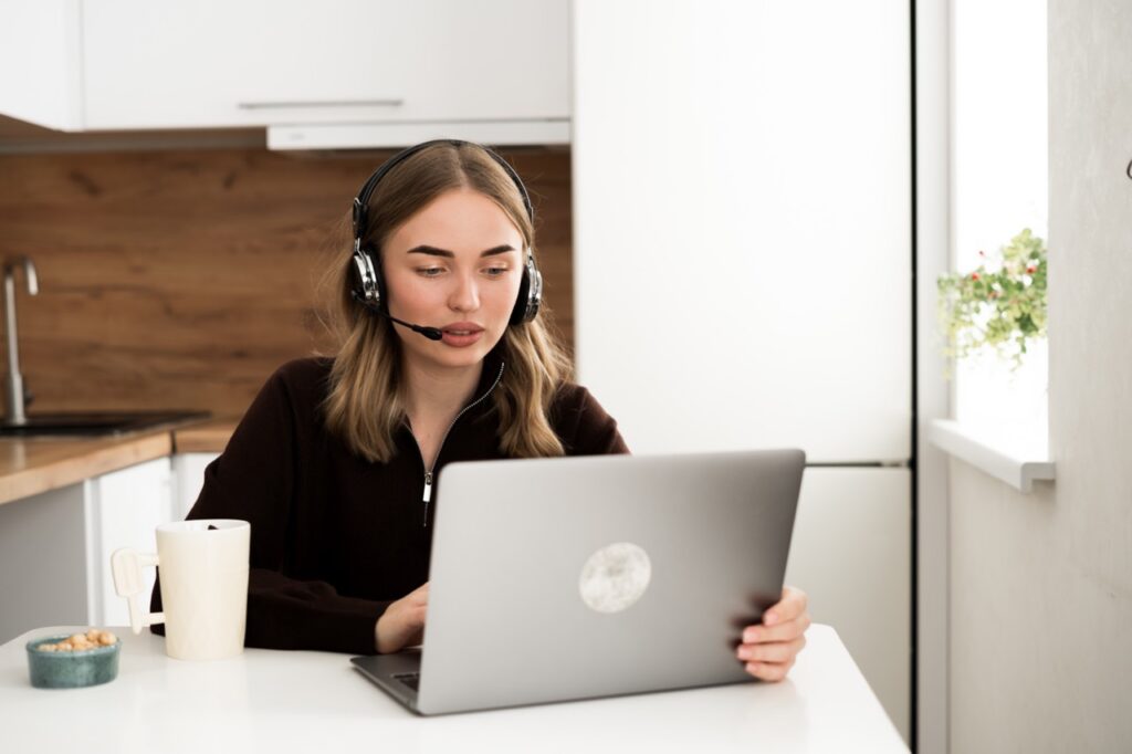Contact center agent working remotely with workforce management and real-time analytics dashboard on screen